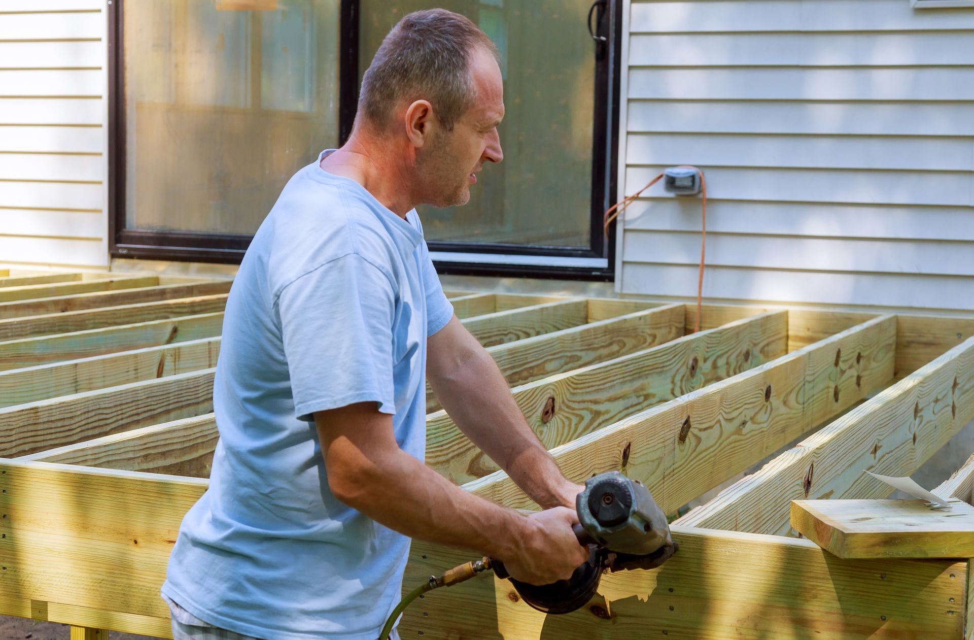  carpenter hammering on a installing of wooden deck patio