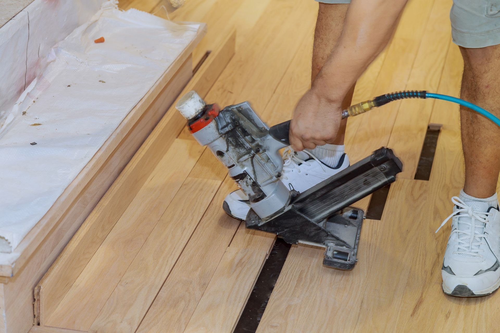 Installing wooden floor in use pneumatic hammer new house